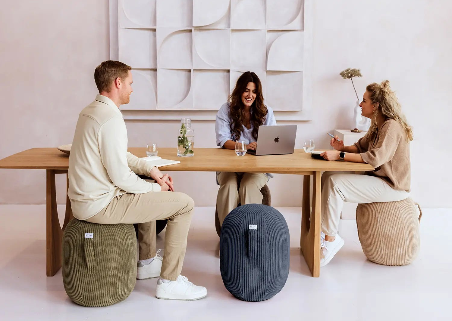 Drei Personen sitzen auf Ballstühlen am Tisch und arbeiten.