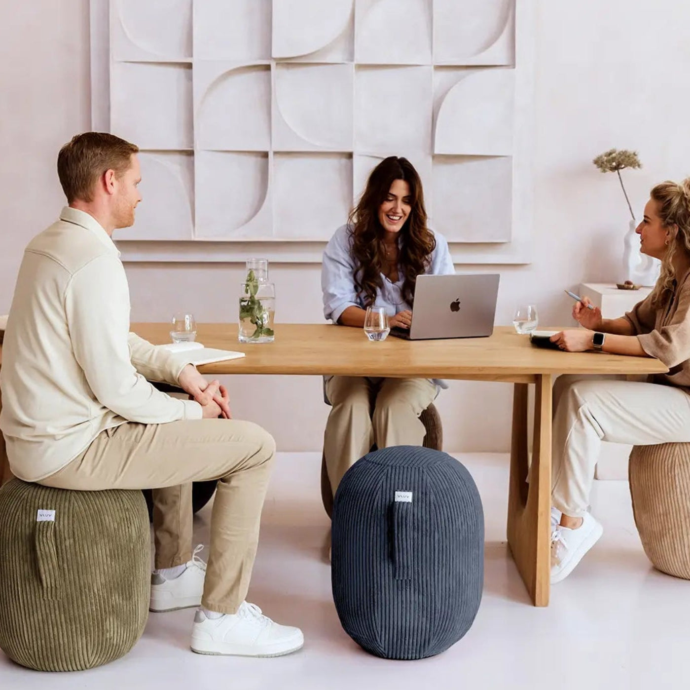 Drei Personen sitzen auf Ballstühlen am Tisch und arbeiten.