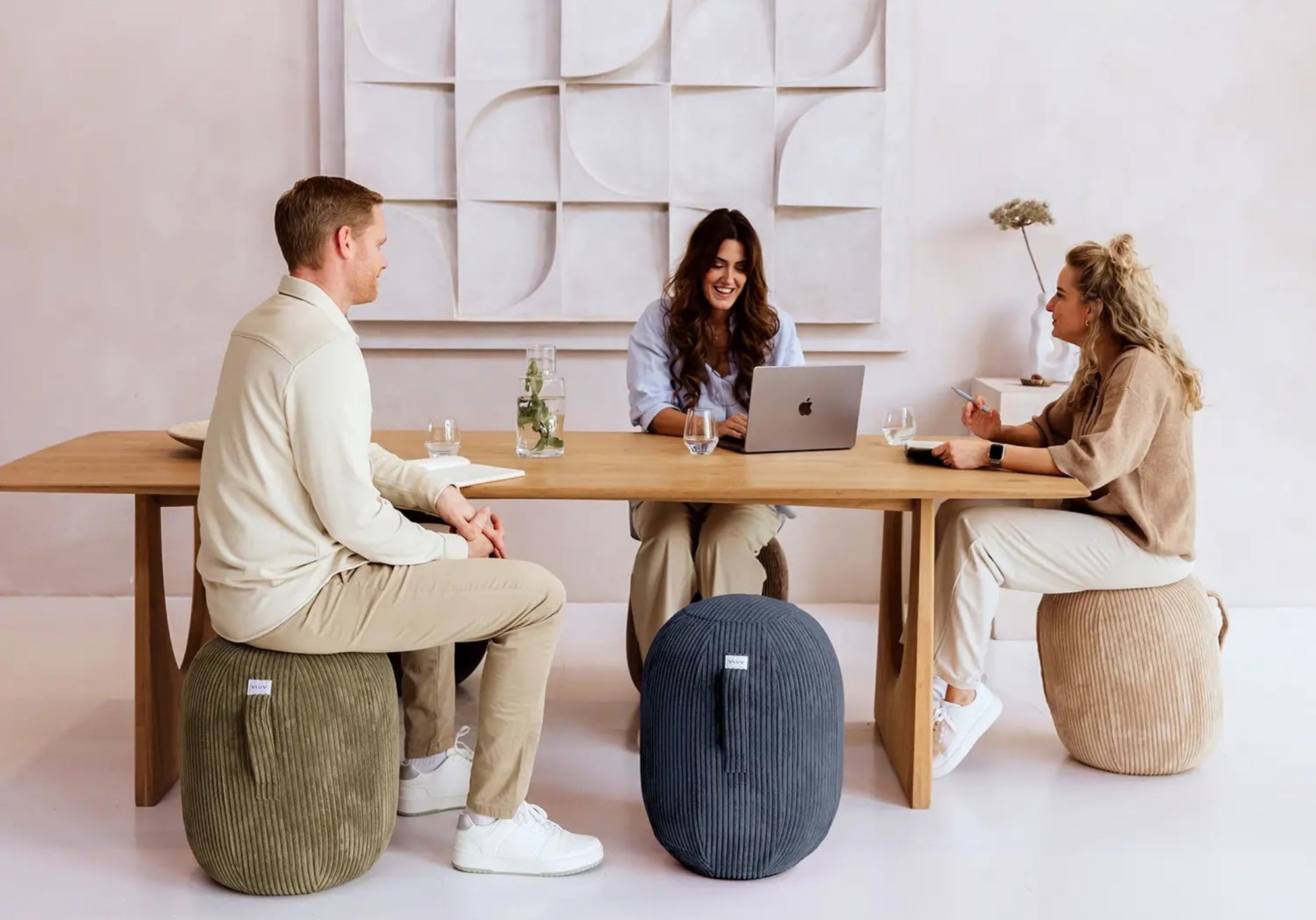 Drei Personen sitzen auf Ballstühlen am Tisch und arbeiten.